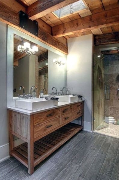 Rustic bathroom with wooden double vanity, exposed beams, and glass-enclosed shower.