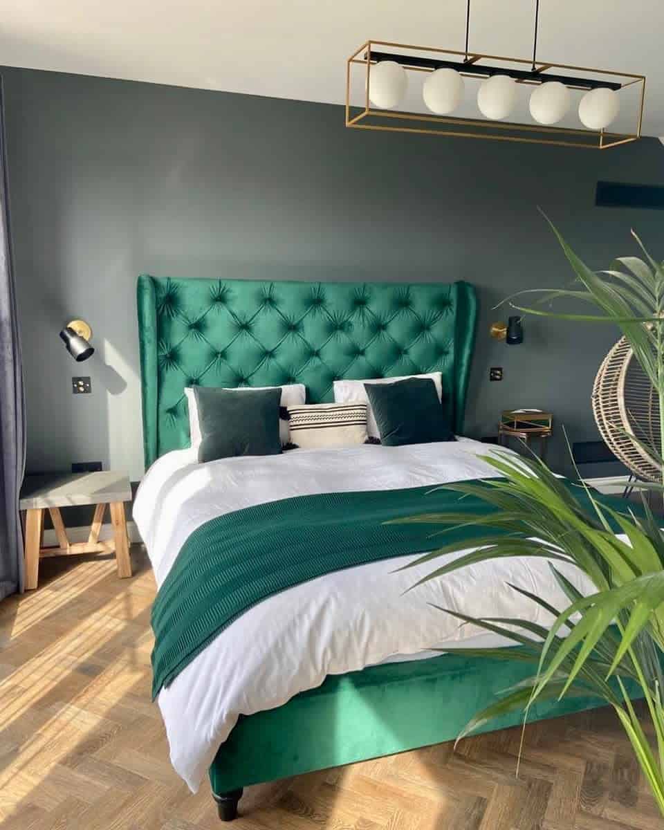 Modern bedroom with emerald green bed, white and green bedding, and a hanging chair