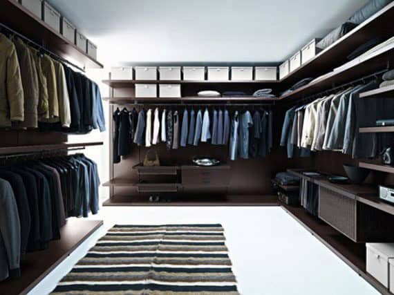 Spacious walk-in closet with organized clothes on hangers, shelves, and a striped rug on the floor