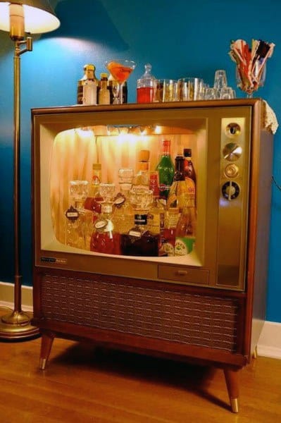 Vintage TV converted into a creative mini bar with illuminated liquor and glassware display.