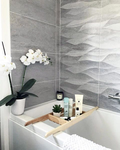 Bathroom with orchid, toiletries on a tray, and wave-patterned grey tiles