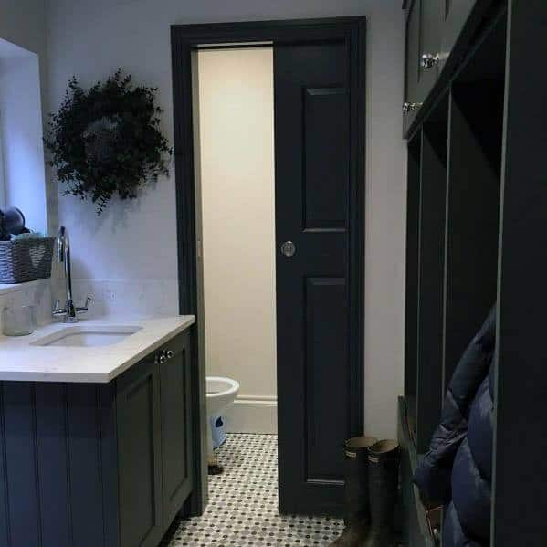 Stylish black pocket door in a modern mudroom with dark cabinetry, a white countertop sink, and patterned tile flooring