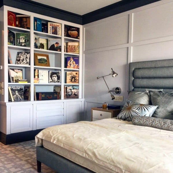 Modern bedroom with built-in bookshelf, wall art, and upholstered headboard.