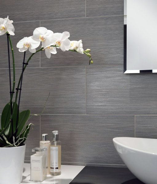 Elegant bathroom with white orchid, toiletries, and a white sink against grey tiled walls