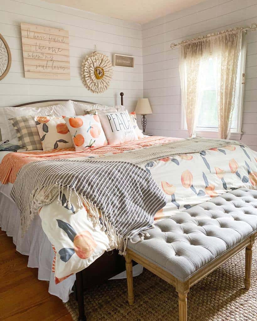 Rustic bedroom with wood paneling, floral bedding, tufted ottoman, and decorative wall art.