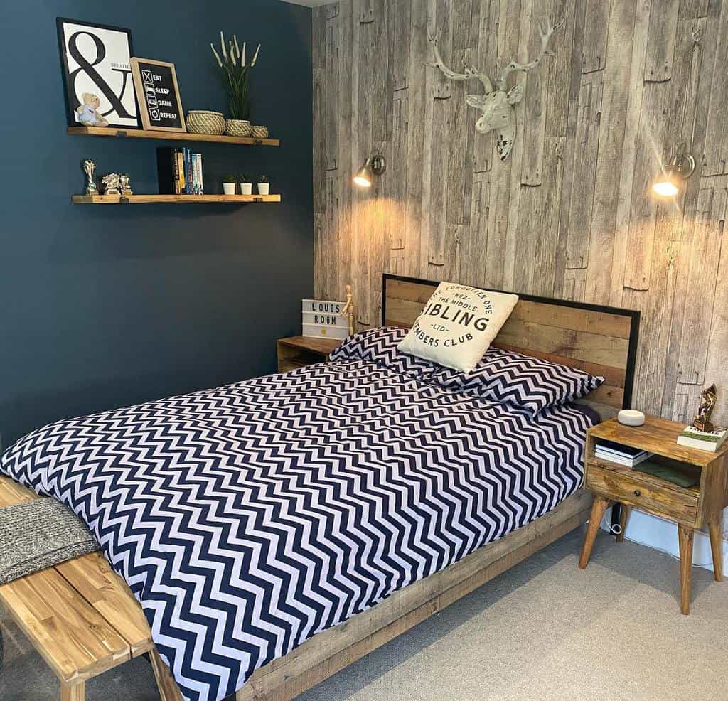 Bedroom with fake wood paneling, antler wall art, floating shelf, and chevron bedding.