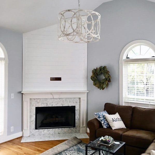 Cozy living room with a corner fireplace, marble tile surround, and shiplap accent wall above.