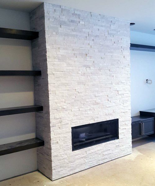 Modern fireplace with a full-wall textured stone tile surround, complemented by dark floating shelves and built-in cabinetry.