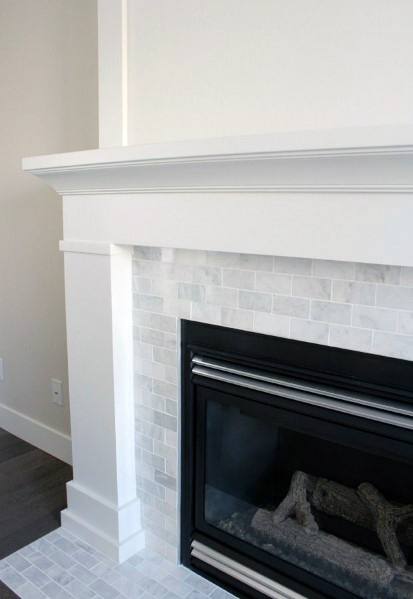 White fireplace with small marble tiles and a sleek black gas insert.