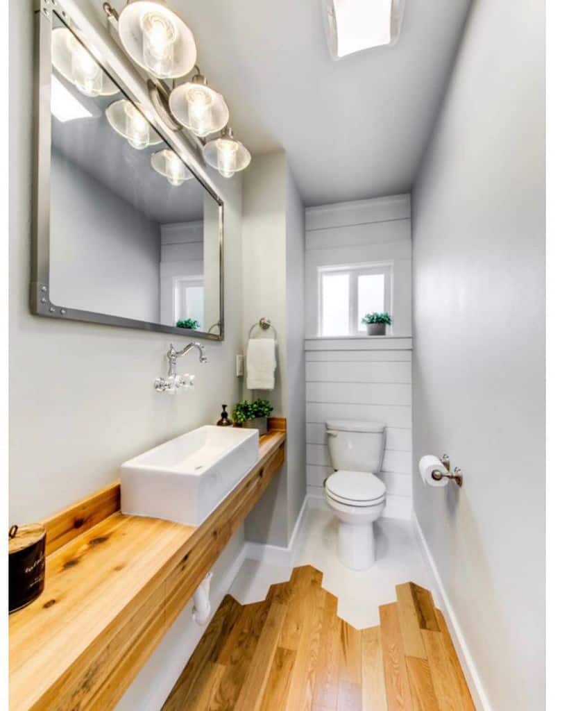 Narrow bathroom with wooden countertop, vessel sink, large mirror, and shiplap wall accents.