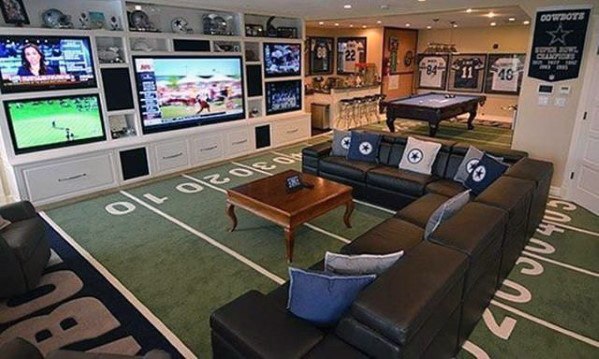 Football-themed mancave with leather sectional, field-patterned carpet, framed jerseys, and a pool table.