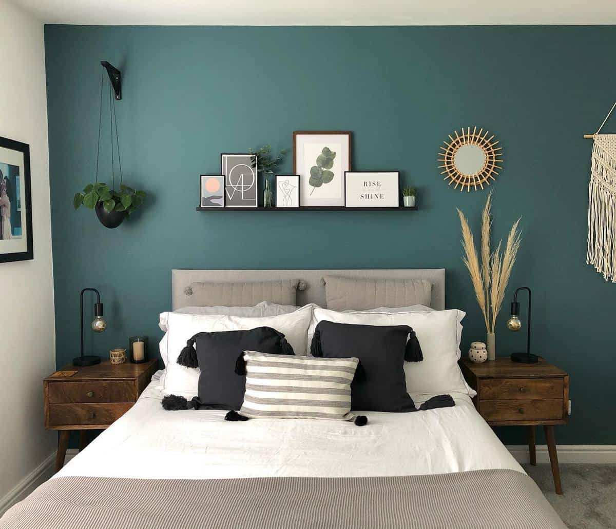 Modern bedroom with teal accent wall, gray bedding, wooden nightstands, and wall-mounted decorations