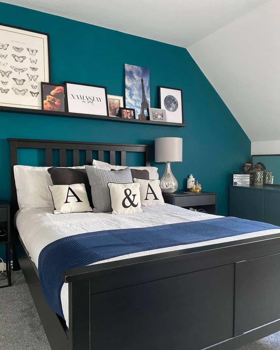 Stylish bedroom with teal walls, a black bedframe, patterned pillows, and framed art gallery above the bed