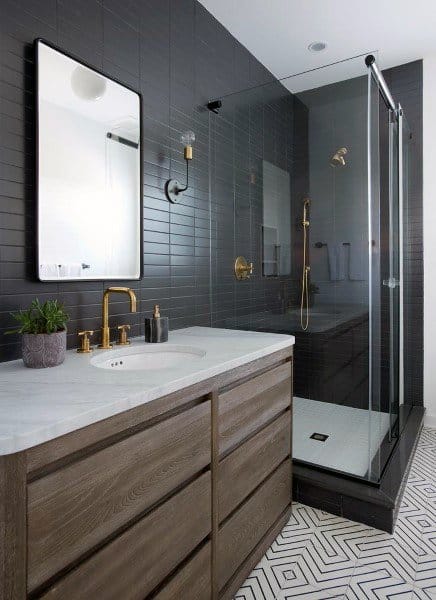 Modern bathroom with rounded rectangle mirror, dark tiled shower, and wood vanity.