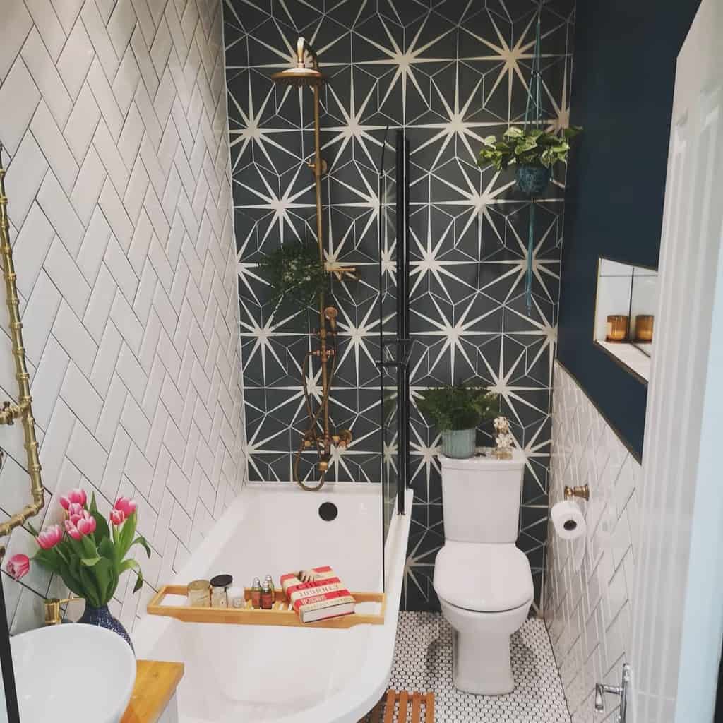 Small bathroom with bold star-patterned tiles, herringbone wall tiles, and a white bathtub with gold fixtures.