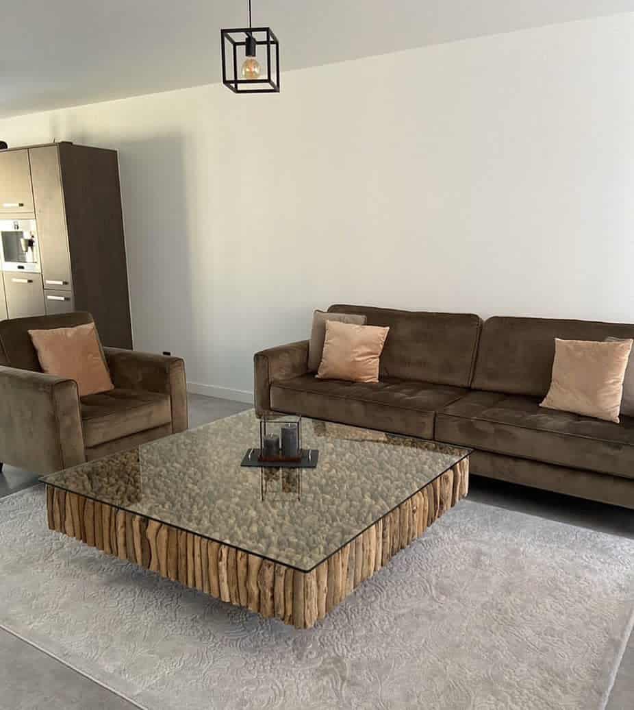 Brown sofa, armchair, and a glass coffee table on a light rug; hanging light fixture overhead