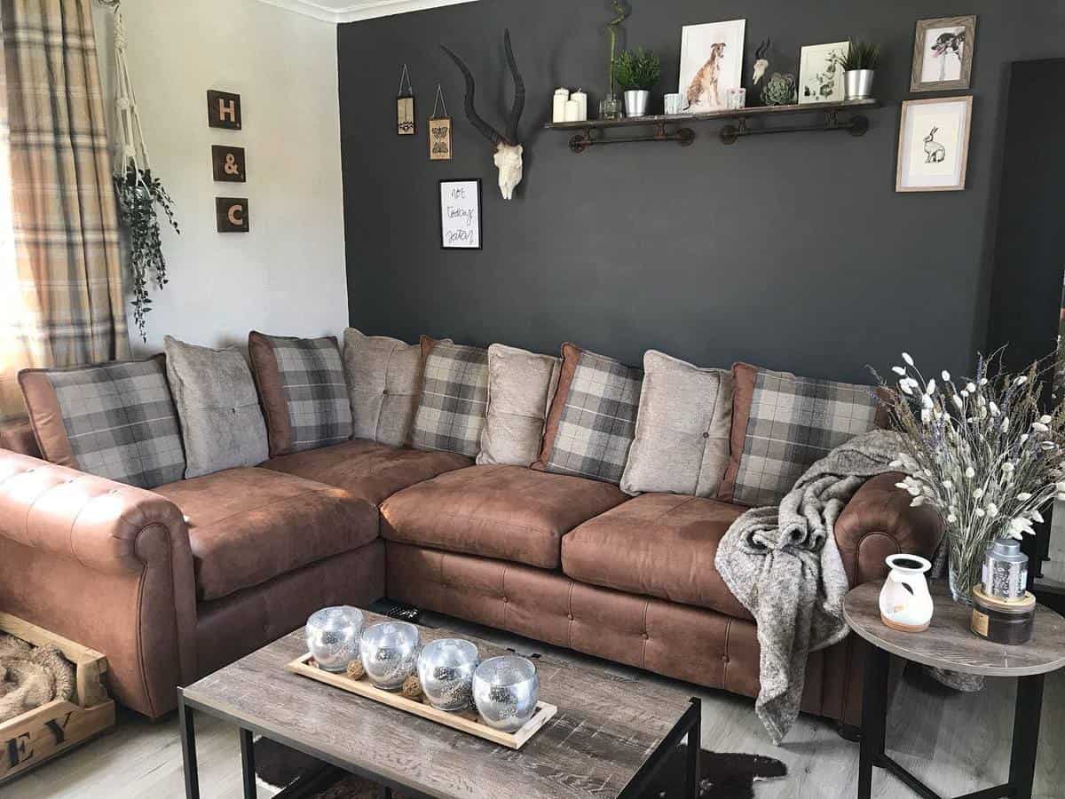 Cozy living room with a plush brown sectional, plaid pillows, wall art, a wooden shelf, neutral tones, and soft lighting