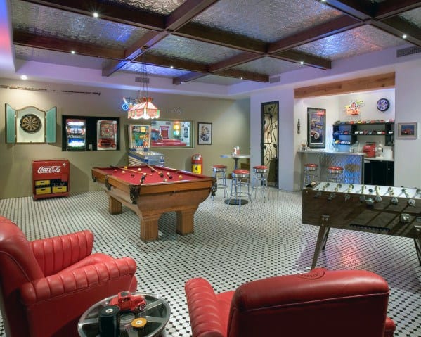 Retro-themed game room with pool table, foosball, dartboard, and red leather lounge chairs.