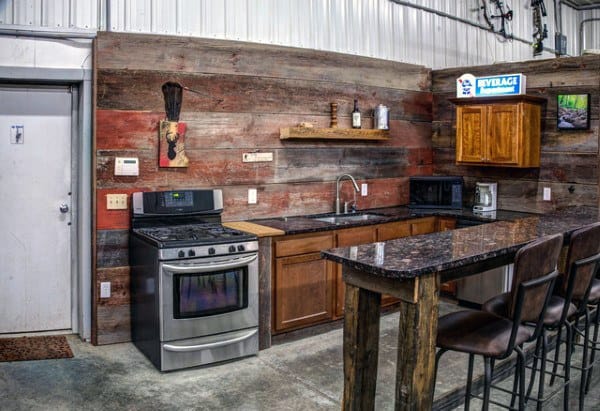 Rustic garage bar with reclaimed wood walls, granite countertop, and stainless steel appliances.