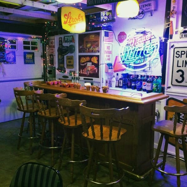 Retro garage bar with wooden stools, neon signs, vintage decor, and a cozy atmosphere.