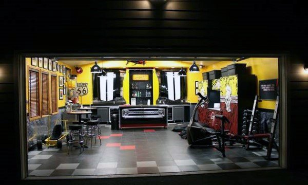 Modern garage bar with yellow walls, car-themed decor, gym equipment, and a sleek bar setup.