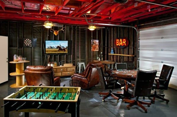 Garage converted into a game room with a bar, foosball table, leather chairs, TV, and dartboard