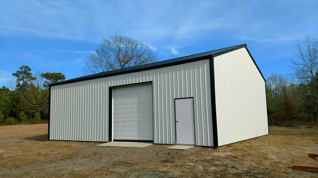 White steel garage shed with a large overhead door and side entry door, located in a rural area.