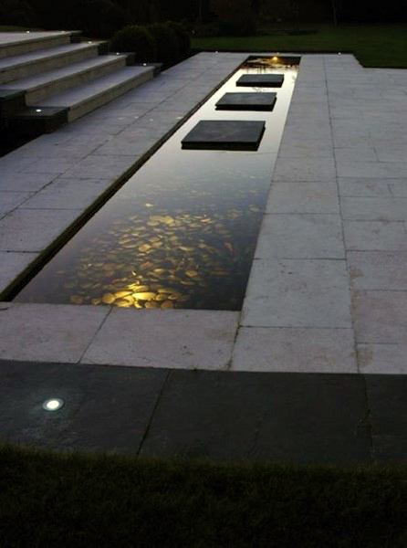 Sleek rectangular pond with floating stone steps and soft lighting reflecting off the water.