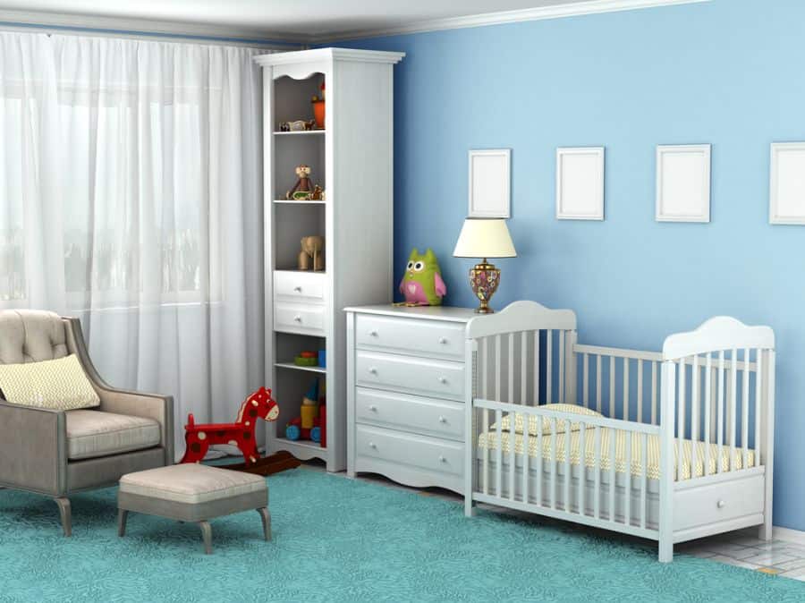 Blue-themed baby room with crib, dresser, rocking horse, and beige armchair.