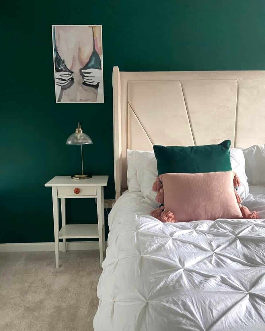 Bedroom with green walls, white bed, and nightstand; art of abstract figure with green accents above the lamp