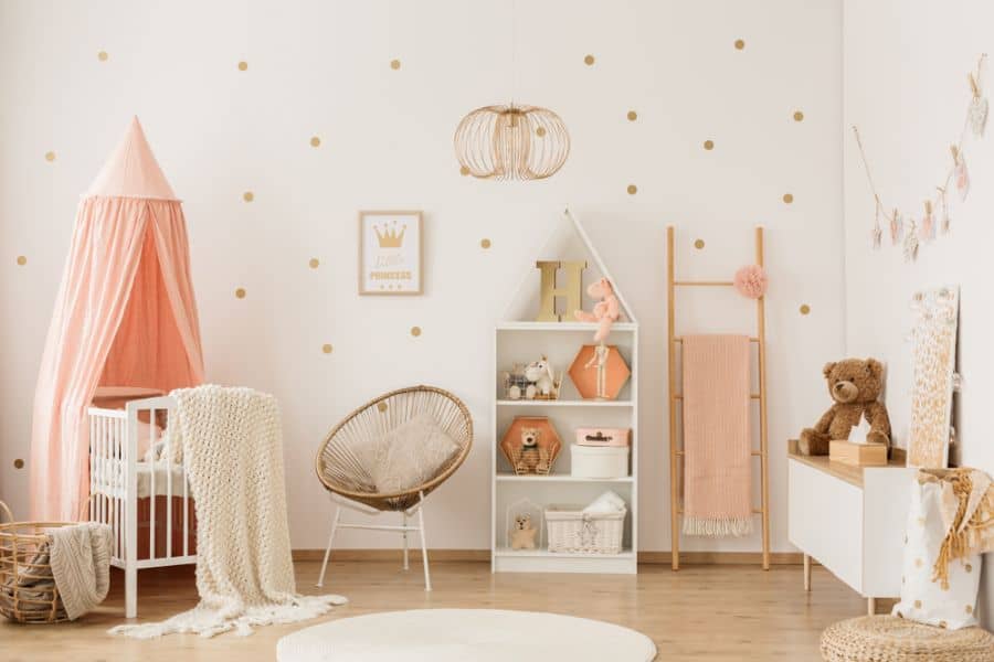 Adorable nursery with a pink canopy crib, rattan chair, and playful wall decor.