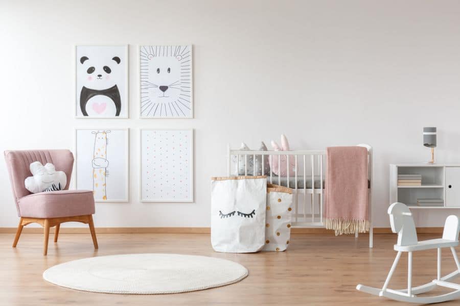 Modern baby girl's room with animal wall art, pink chair, and white crib.