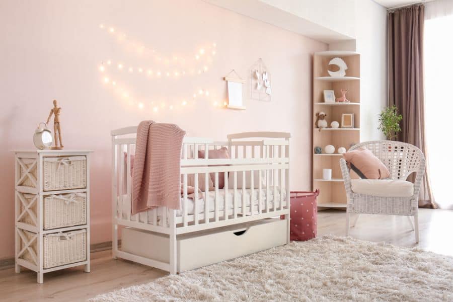 Dreamy baby girl's room with pink walls, cozy crib, and soft lighting decorations.