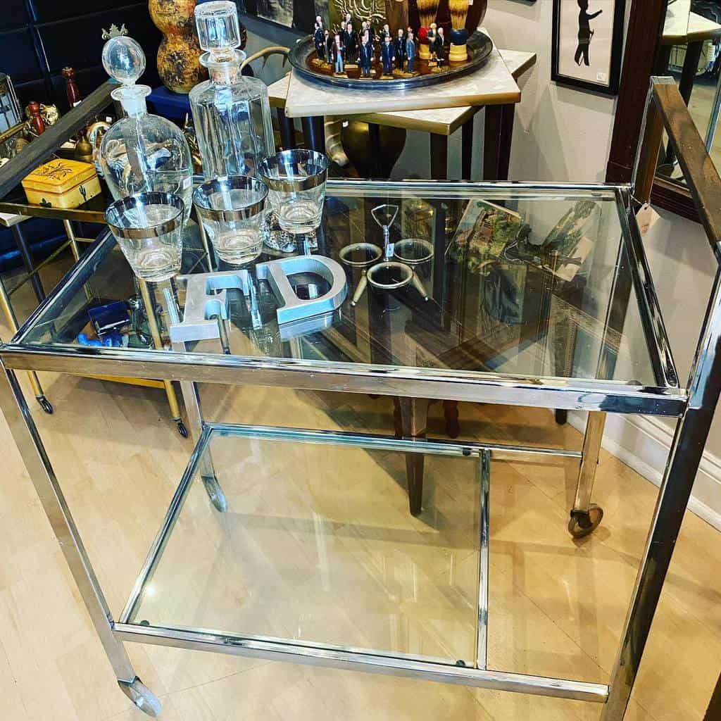 Sophisticated silver bar cart with crystal decanters, tumblers, and decorative items.