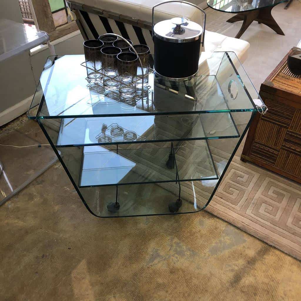 Modern glass bar cart with an ice bucket, glass tumblers, and geometric design.