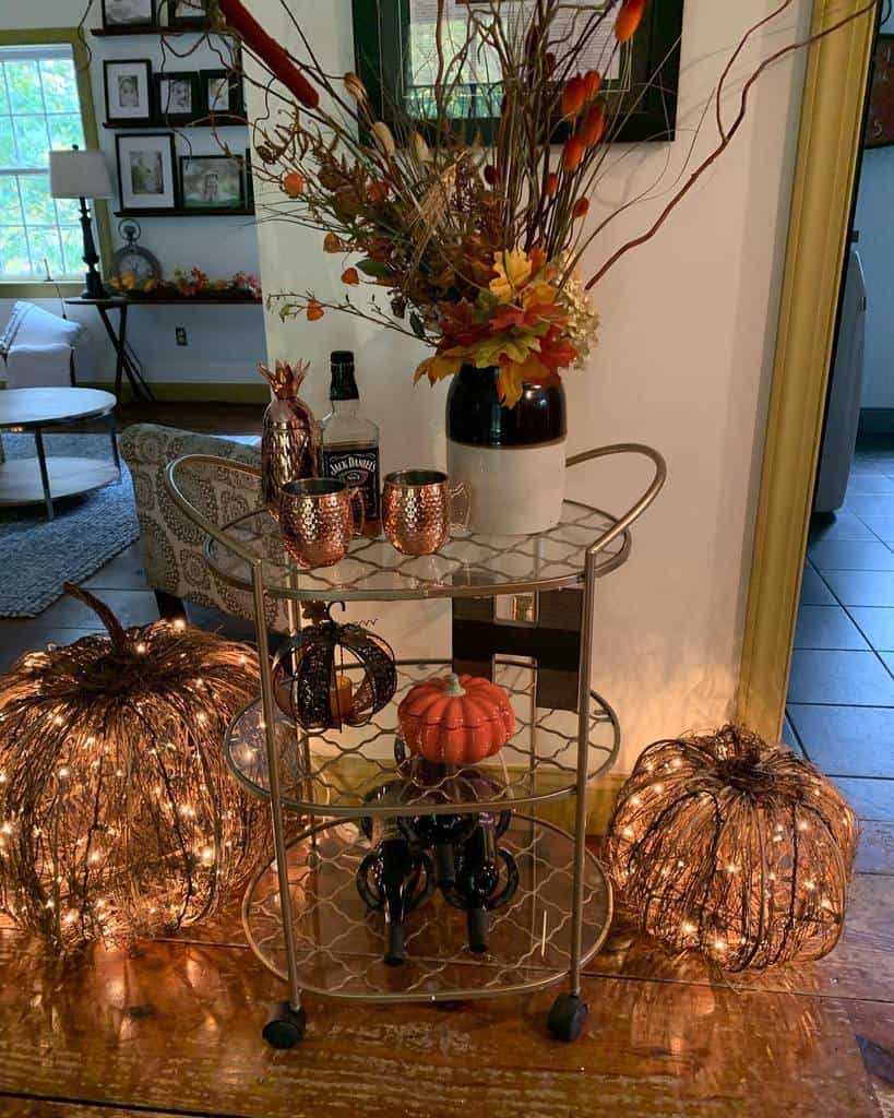 Halloween-themed bar cart with copper mugs, Jack Daniels, fall florals, and decorative pumpkins.