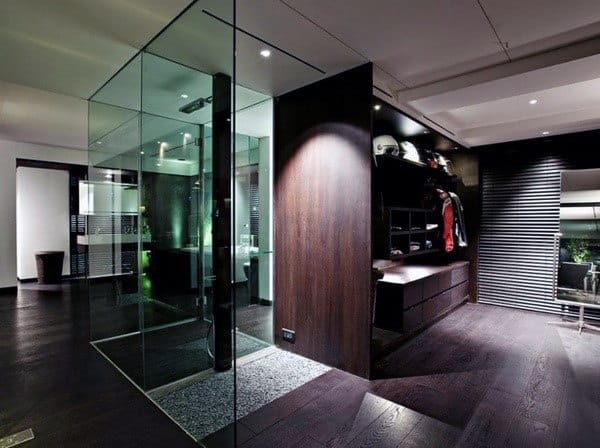 Modern interior with glass walls, dark wood floors, sleek furniture, and a display of helmets and clothes