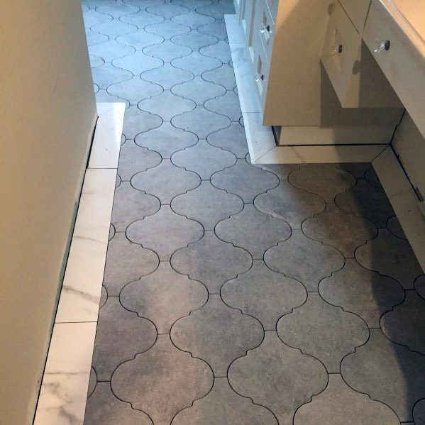 Grey scalloped tile floor with white cabinets on the right