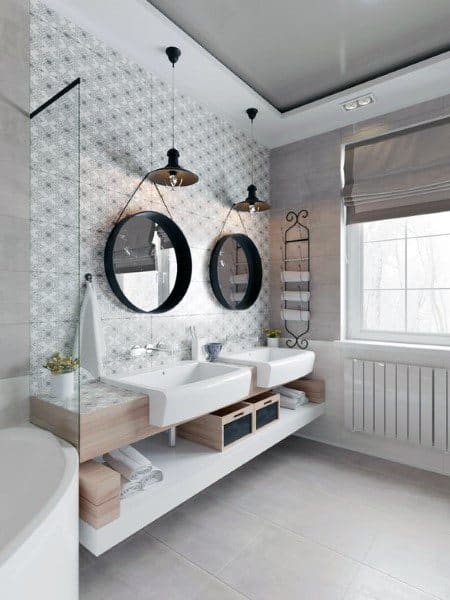 Modern double vanity bathroom with round mirrors, hanging lights, and open shelving.