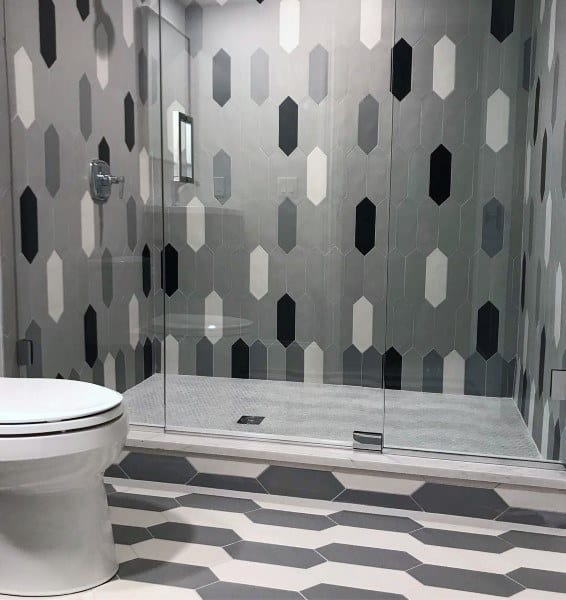 Bathroom with grey, black, and white geometric wall tiles and matching floor tiles.