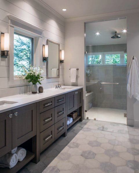 Modern bathroom with brown cabinets, hexagonal tile flooring, and glass walk-in shower.