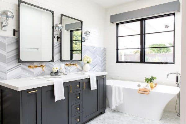 Bathroom with grey and white herringbone tile backsplash, dark vanity, and freestanding tub.