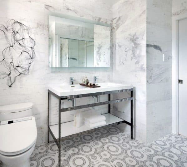 Contemporary bathroom with marble walls, a modern sink, circular patterned floor, and abstract wall art