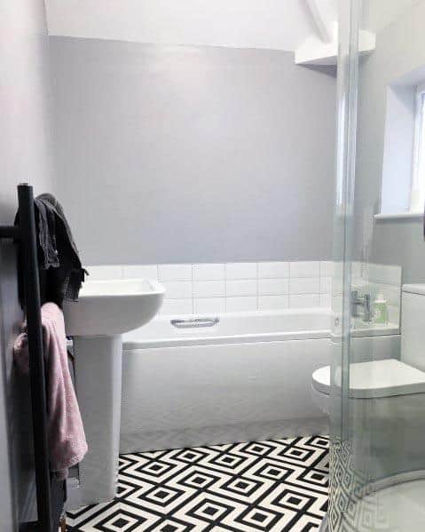 Bathroom with light grey walls, geometric patterned flooring, and a clean modern bathtub and shower.