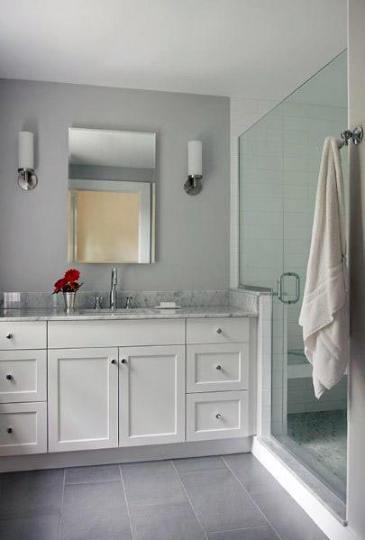 Modern bathroom with white vanity, mirror, grey walls, and glass shower