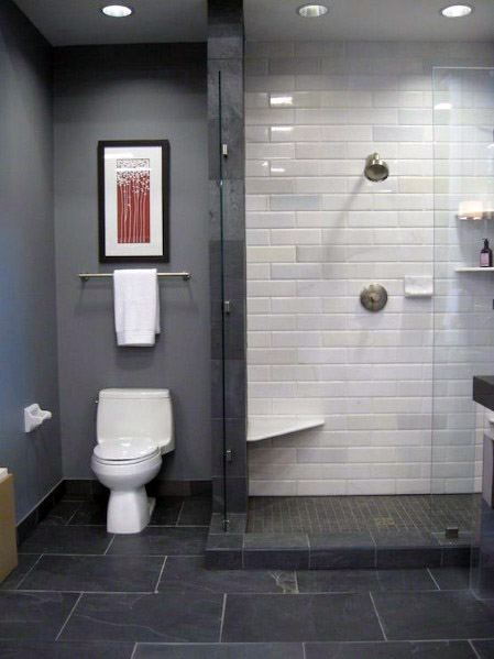 Modern bathroom with glass shower, grey and white tiles, toilet, and framed art above towel bar