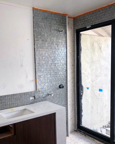 Grey hexagonal tile wall and large window in a bathroom under construction