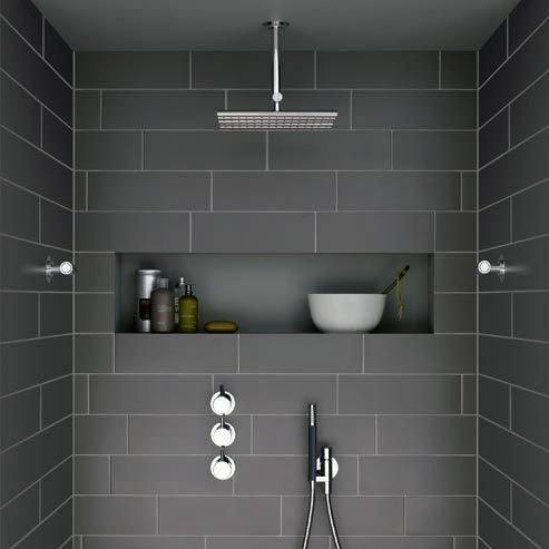 Modern shower with grey tiles, built-in shelf for toiletries, and a rainfall showerhead