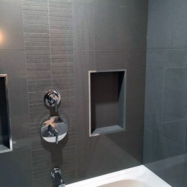 Modern bathroom with grey tiles, chrome fixtures, and built-in shower niches above a bathtub