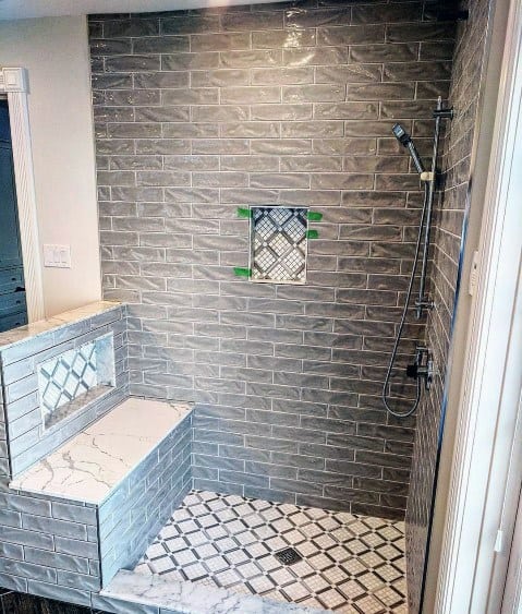 Modern grey-tiled shower with a bench and geometric floor pattern